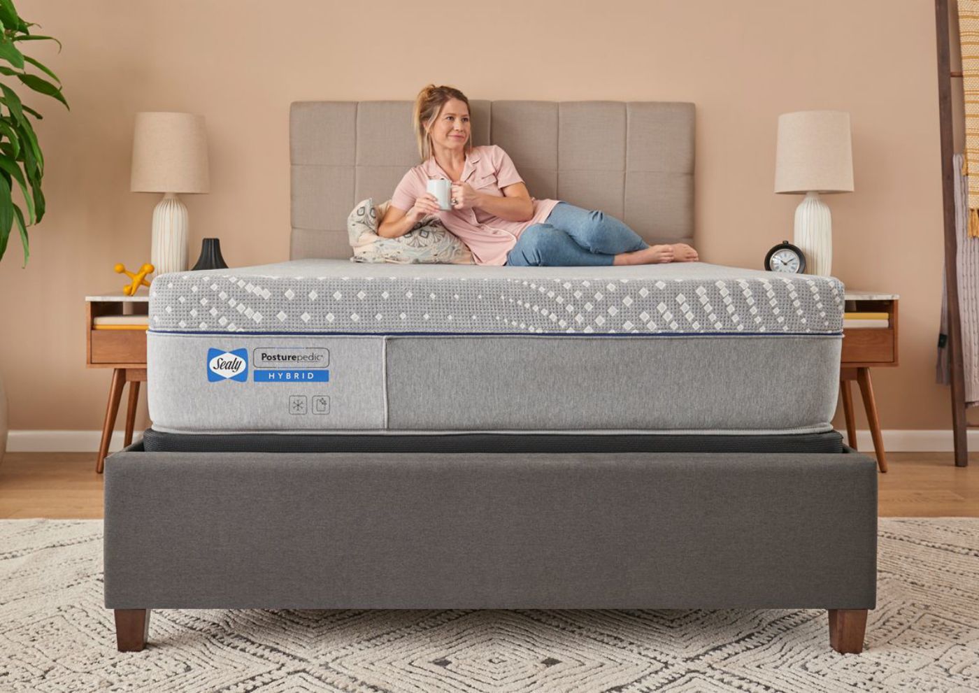 Room View with woman sitting on the Sealy Posturepedic Hybrid Lacey Firm Mattress in Twin XL Size | Home Furniture Plus Bedding