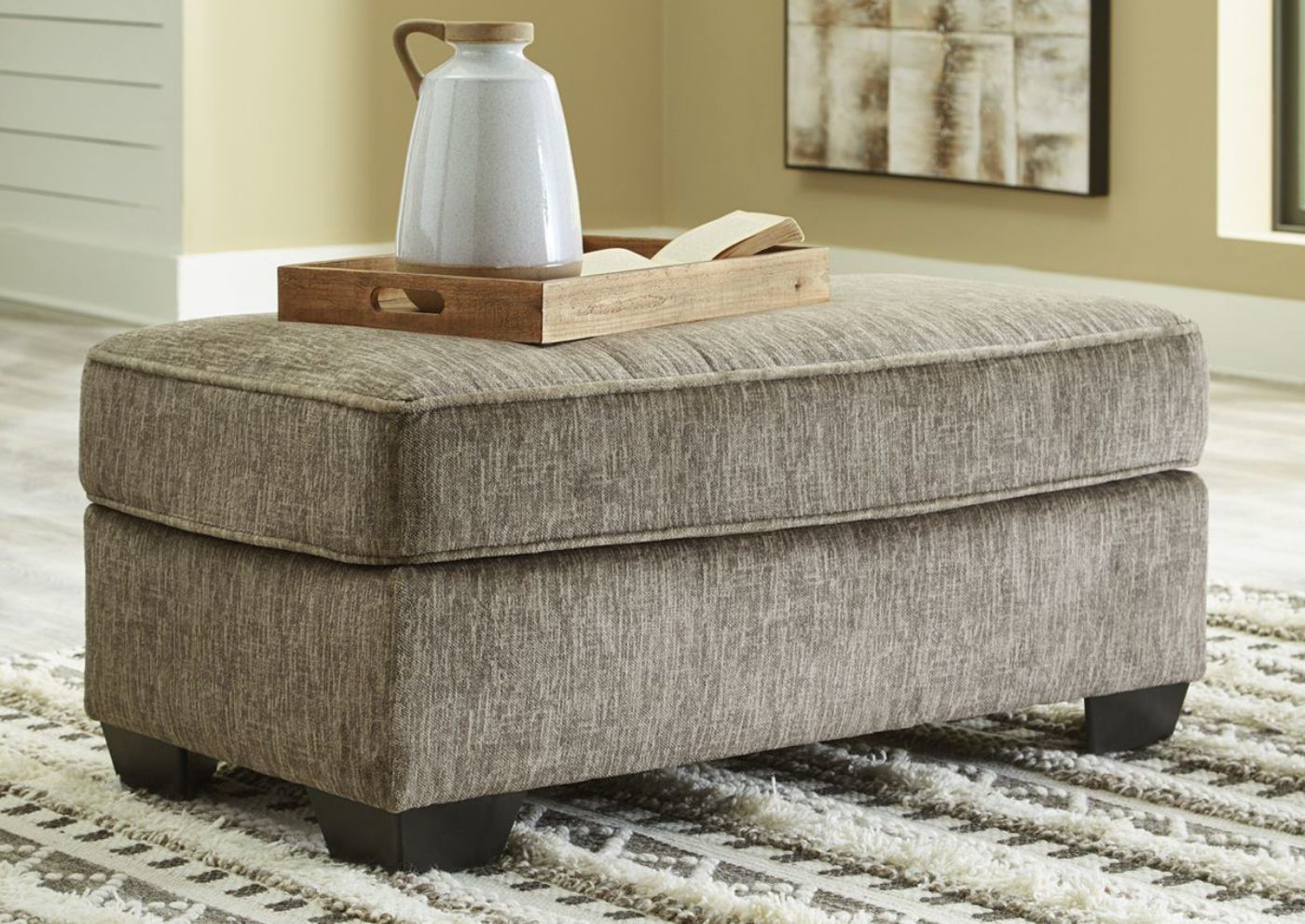 Angled View of the Chocolate Brown Olin Ottoman by Ashley Furniture in A Room View | Home Furniture Plus Bedding