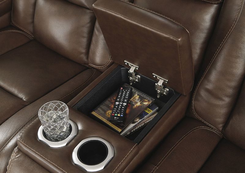 Close Up View of the Console with Cup Holders on the Man-Den Power Reclining Loveseat in Mahogany Brown by Ashley Furniture | Home Furniture Plus Bedding
