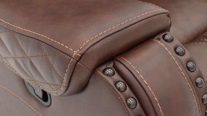 Closeup View of the Nailhead Trim and Stitching  on the Arm of the Elliot Leather Glider Recliner in Brown by Man Wah | Home Furniture Plus Bedding